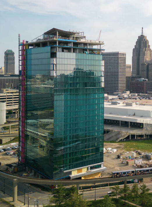 Glas-Hochhaus im Bau in einer Stadt, umgeben von Bürogebäuden und einer erhöhten Verkehrsführung